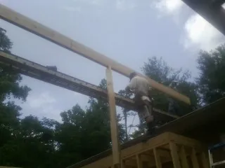 Carpenter setting a ridge beam over a new addition frame — Ice Dam Removal by Roofing Brothers in Montchanin