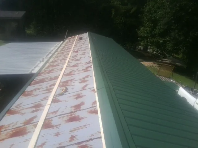 Old rusted panels beside newly installed green metal roofing — Wind Damage Roof Repair by Roofing Brothers in Montchanin