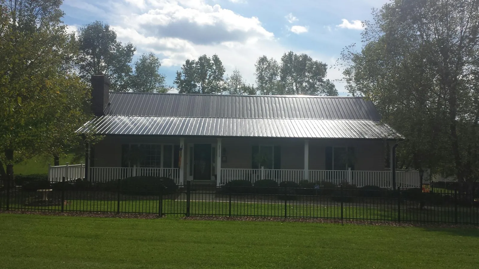 Gray metal roof on a brick ranch with a full width front porch — Gutter Guard Installation work by our crew in Montchanin