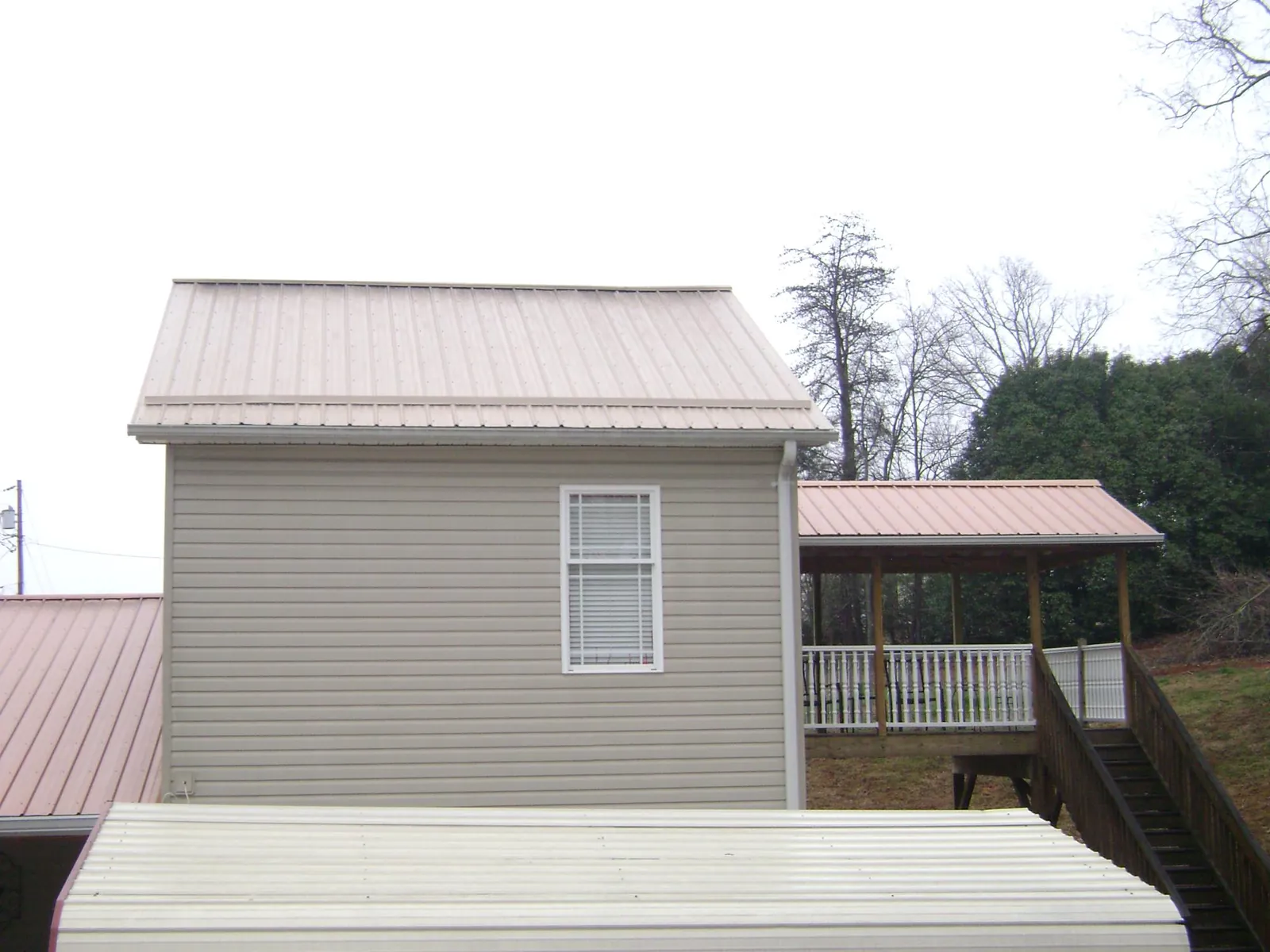 Tan metal roofs on a two story addition and attached porch, from a Roof Replacement job in Montchanin