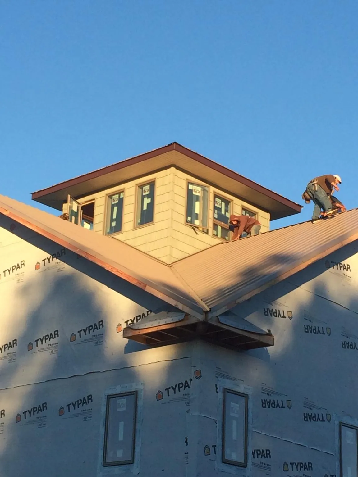 Roofers working around a rooftop cupola on a new metal roof at sunset — Roof Waterproofing in Montchanin by Roofing Brothers
